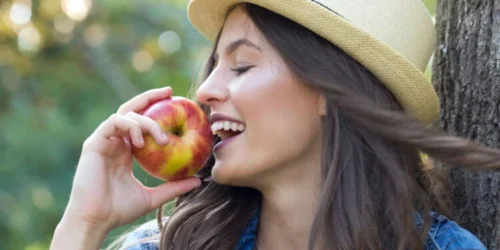 photo of a women in a hat eating an apple